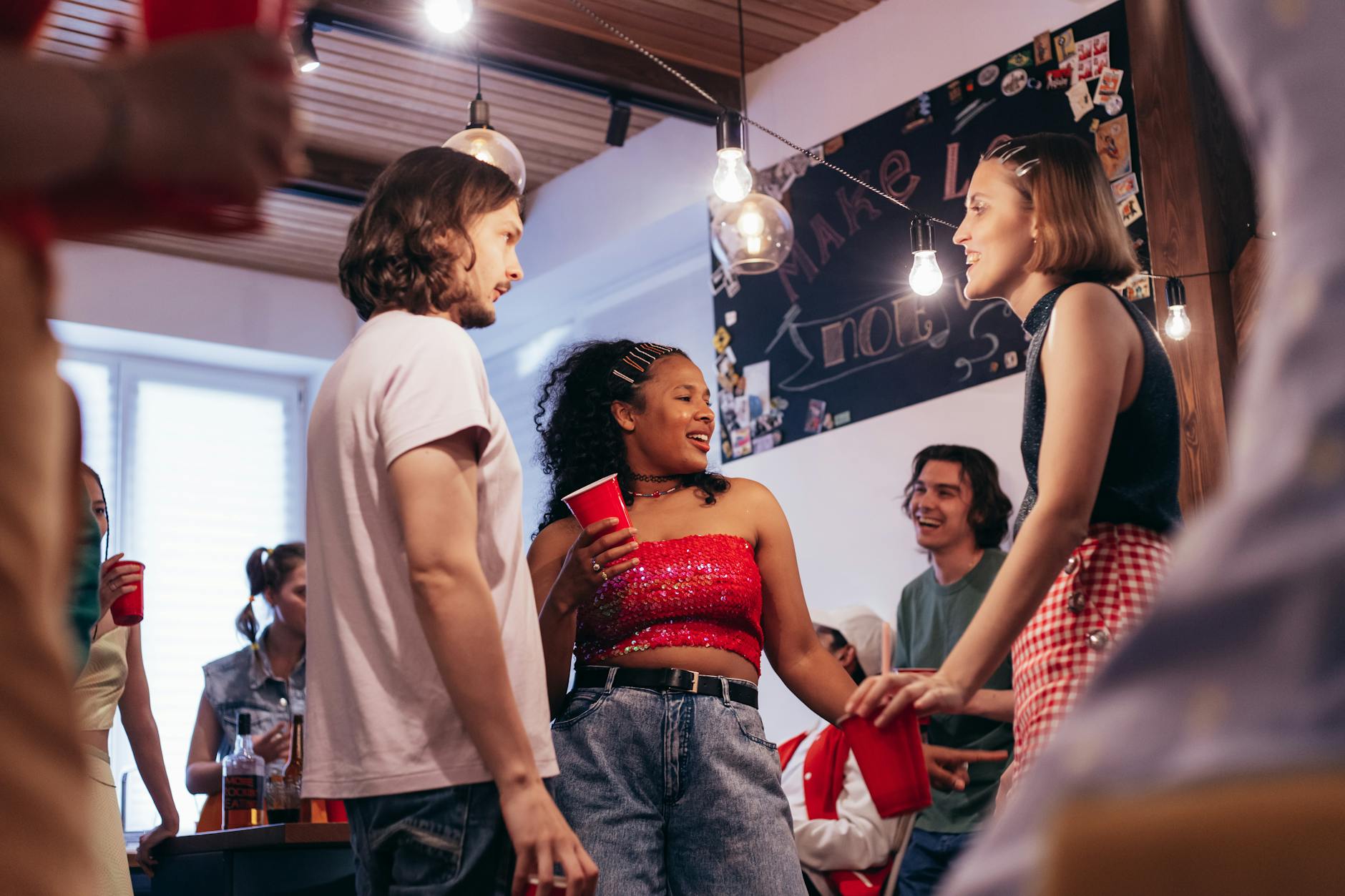Group of friends enjoying a lively indoor party with drinks and conversation.